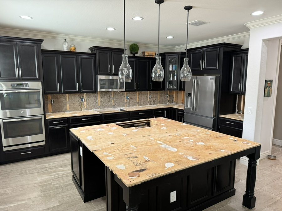 A kitchen mid tear-out: old countertops and backsplash removed, cabinets and appliances still in place