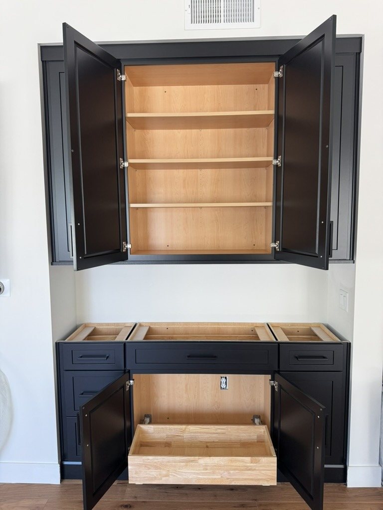 Black shaker cabinetry installed in a Scottsdale, AZ home, doors open to show maple interiors and a pull-out drawer, before the countertops go on