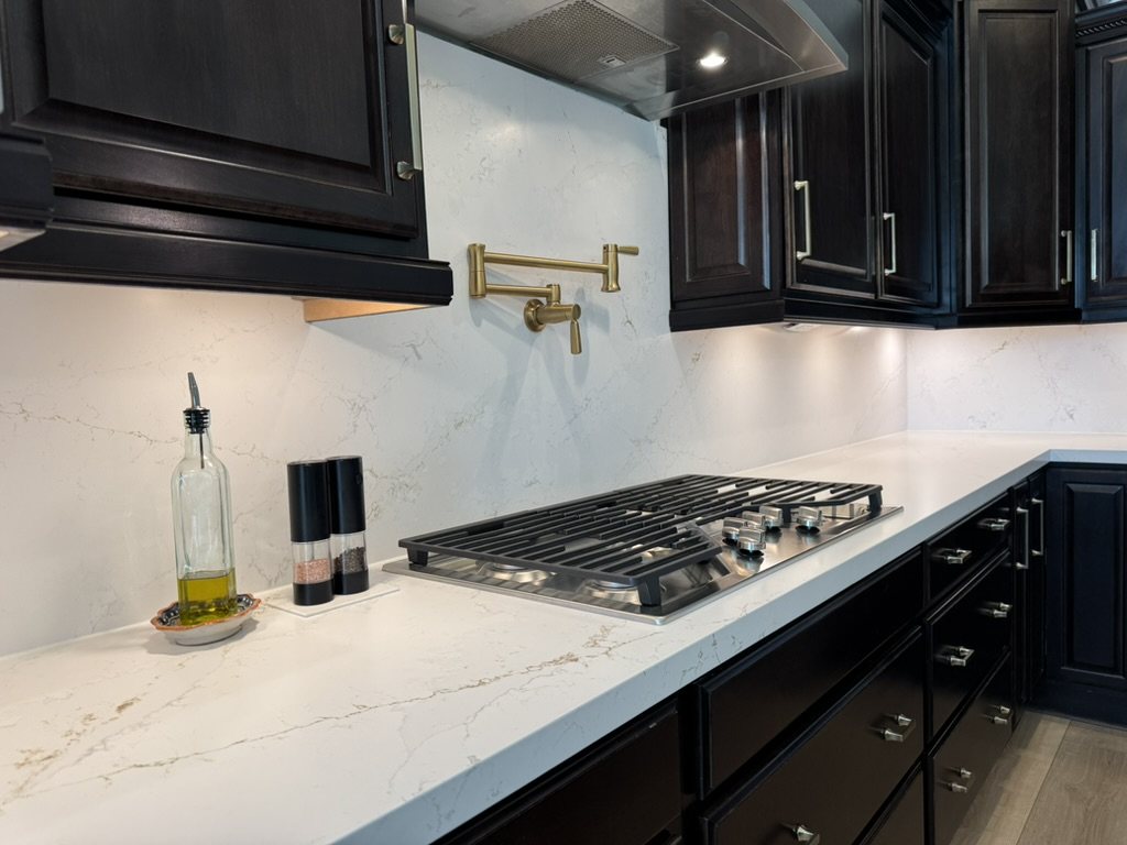 Cooktop wall with vein-matched quartz backsplash and brass pot filler, Gilbert, AZ kitchen