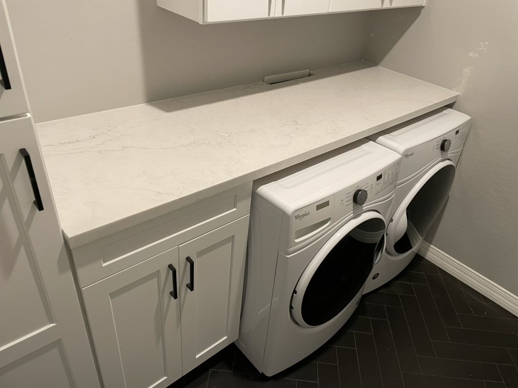 Quartz counter and open shelf above a stacked washer and dryer, Mesa, AZ laundry room