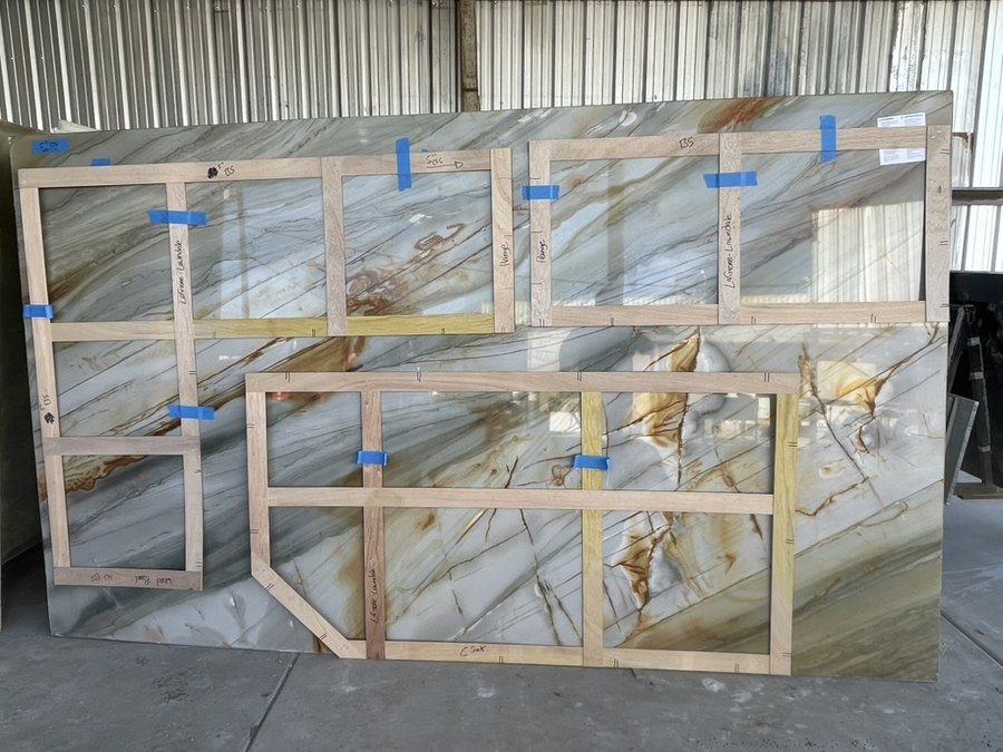 Wooden templates laid out on a heavily veined slab to plan seam placement and veining direction before fabrication, Markell Designs